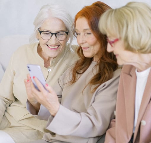 A group of three old women who are happy during a video chatting on the smartphone of one of them.