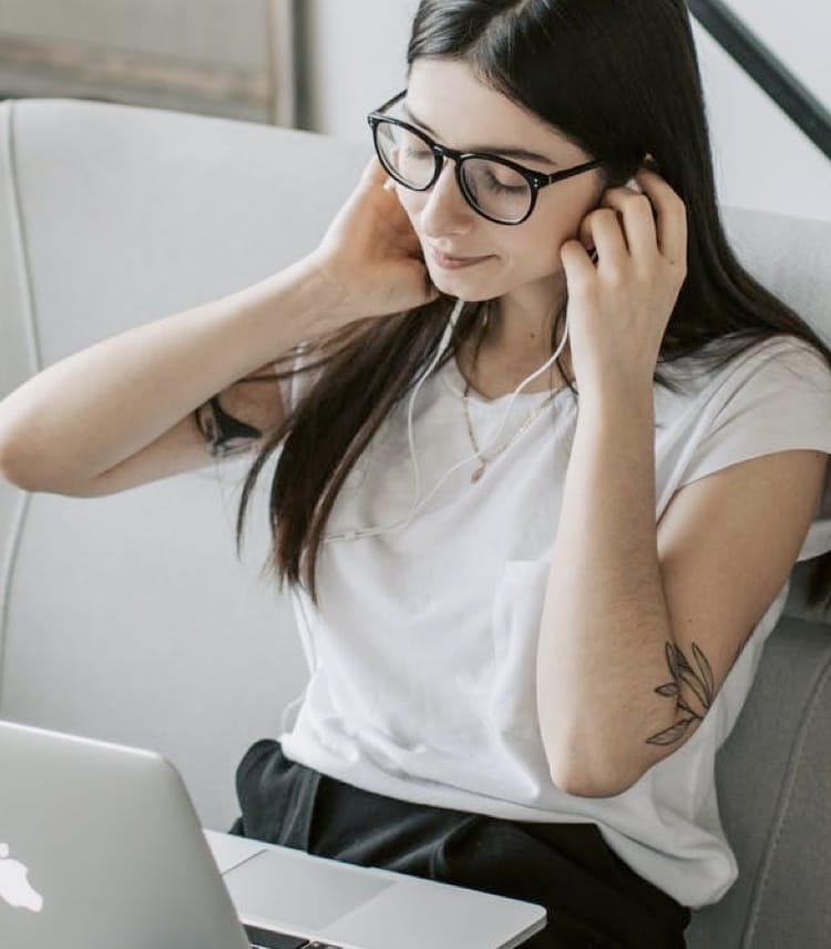 A woman who have eyes closed in her living room is listening to music with her headphones.